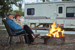 Elderly couple at their campsite enjoying a campfire